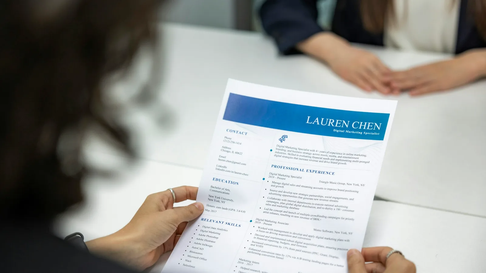 A recruiter reading a printed resume across the table from an applicant